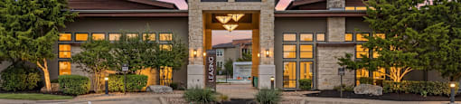 A building with a sign in front of it surrounded by bushes.