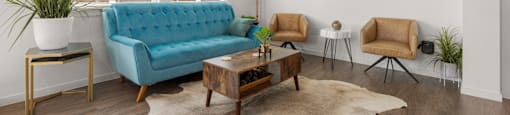A living room with a blue couch, two chairs, and a rug.