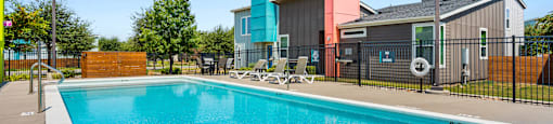A swimming pool surrounded by a black fence with a lifebuoy hanging on it.