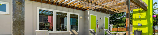 A wooden pergola is over a set of lounge chairs.