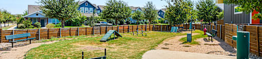 A playground with a green slide and a wooden fence.