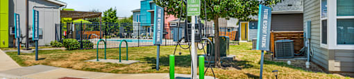 A green and white sign is on a pole in the middle of a parking lot.