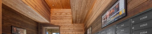 A room with a wooden ceiling and walls, filled with mailboxes on the walls and a mailbox on the floor.
