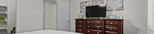 A bedroom with a bed, dresser, and television.