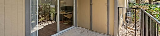 A balcony with a sliding glass door and a brown door.