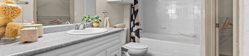 A white bathroom with a toilet, sink, and mirror.