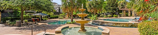 A fountain in the middle of a pool surrounded by trees.