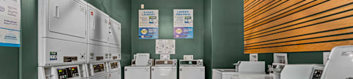 A laundromat with washers and dryers lined up.