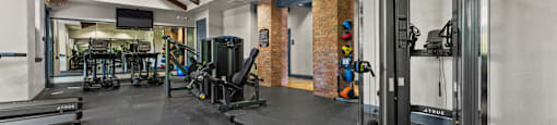 A gym with a variety of equipment including treadmills, weights, and exercise machines.