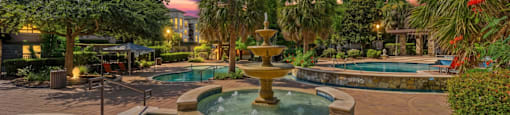 A fountain in the middle of a pool surrounded by trees.