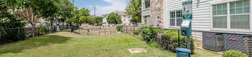 A grassy area in front of a building with a sign on a post.