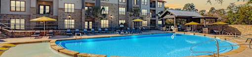 A large swimming pool is surrounded by a resort style building.