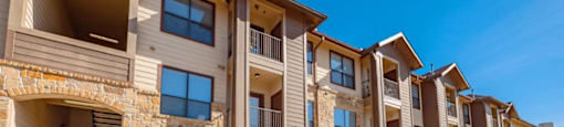 A row of modern apartment buildings with garages and balconies.