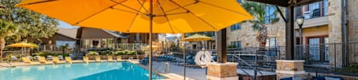 A patio with a table and chairs under a yellow umbrella.