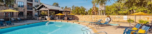 A person is sitting by the poolside under a tree.