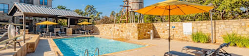 A pool area with sun loungers and a yellow umbrella.