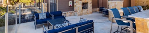 A patio with a stone fireplace and blue couches.