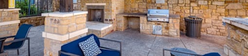 A patio with a stone fireplace and blue couches.
