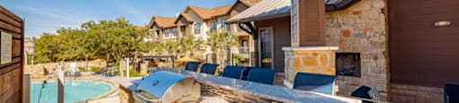 A sunny day at a poolside with a stone barbecue grill.
