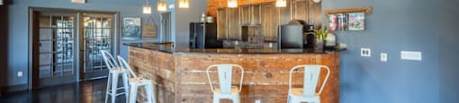 A bar with white chairs and a wooden counter.