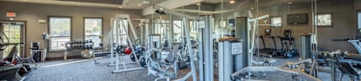 A spacious gym with a variety of equipment and a ceiling fan.