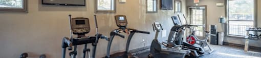 A gym with treadmills, elliptical machines, and a television.