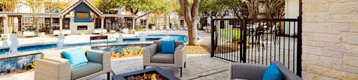 A patio with a fire pit and chairs.