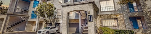 A car is parked in front of a two-story apartment building.