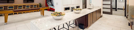 A modern kitchen with a white marble island and wooden cabinets.