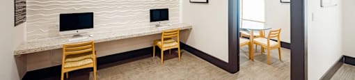 A room with a desk, chairs, and a computer monitor.