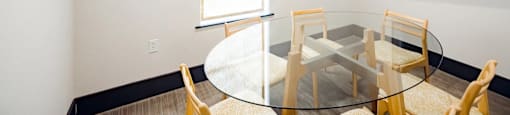 A glass table with chairs around it in a room.