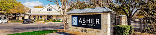 A sign for Asher Apartments is in front of a building.