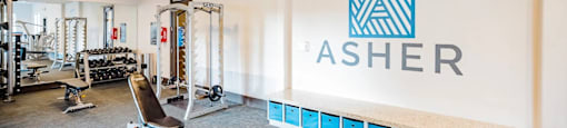 A gym with a row of blue bins and a wall with the word "ASHER" on it.