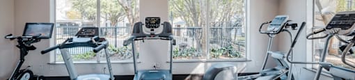 A gym with treadmills, exercise bikes, and a television.