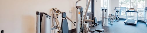 A gym with a variety of equipment including a treadmill, a stationary bike, and a weight machine.
