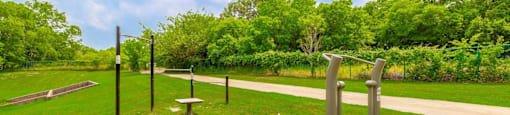 A park with a bench and a sculpture in the middle of a grassy area.