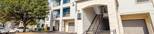 A two-story apartment building with a garage door and a balcony on the second floor.
