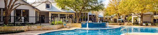 A swimming pool surrounded by a gravel area and trees.