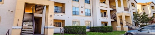 A row of apartment buildings with a car parked in front.