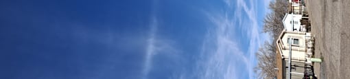 A row of houses with a blue sky and clouds above them.