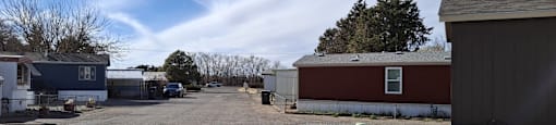 A gravel lot with a blue house and a red building.