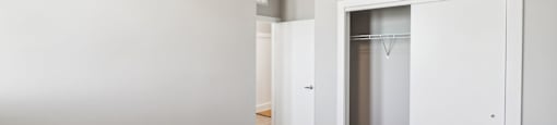 a bedroom with white walls and a closet with a mirrored closet door