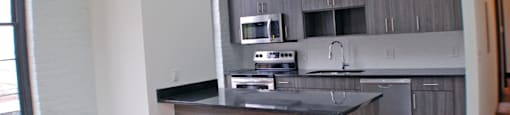 A kitchen island with a black countertop and wooden cabinets.