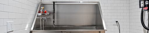 A stainless steel sink in a kitchen with white tiled walls.