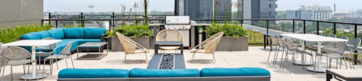 A patio with a couch, chairs, and a table with a view of the city.