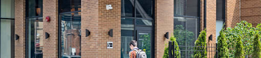 A man is standing in front of a building with the number 2845 on it.
