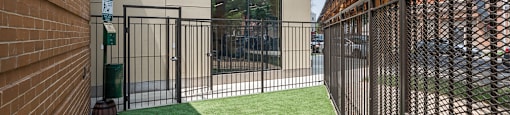 A small fenced in area with a green lawn.