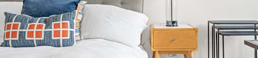 A bedroom with a bed, nightstand, and a painting on the wall.