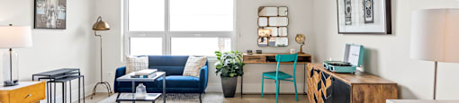 A living room with a blue couch and a white bedspread.