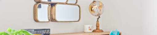 A blue chair sits in front of a desk with a mirror above it.